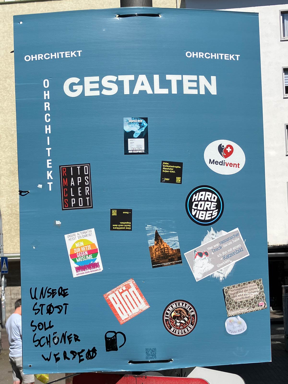 Gestalten-Plakat am Merianplatz in Frankfurt mit immer mehr Aufklebern