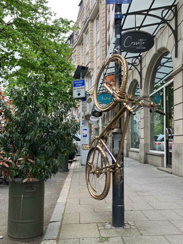 Goldenes Fahrrad hochkant befestigt an Straßenlaterne in Frankfurt