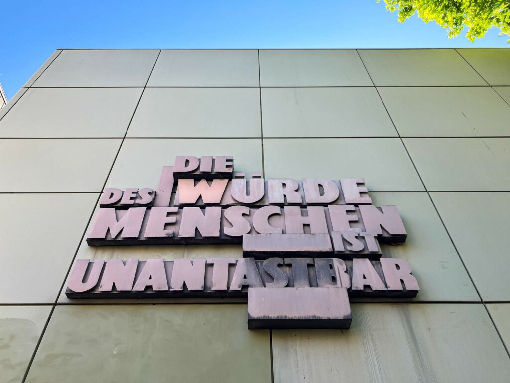 Großer Schriftzug „Die Würde des Menschen ist unantastbar“ hängt an Fassade im Gerichtsviertel in Frankfurt.