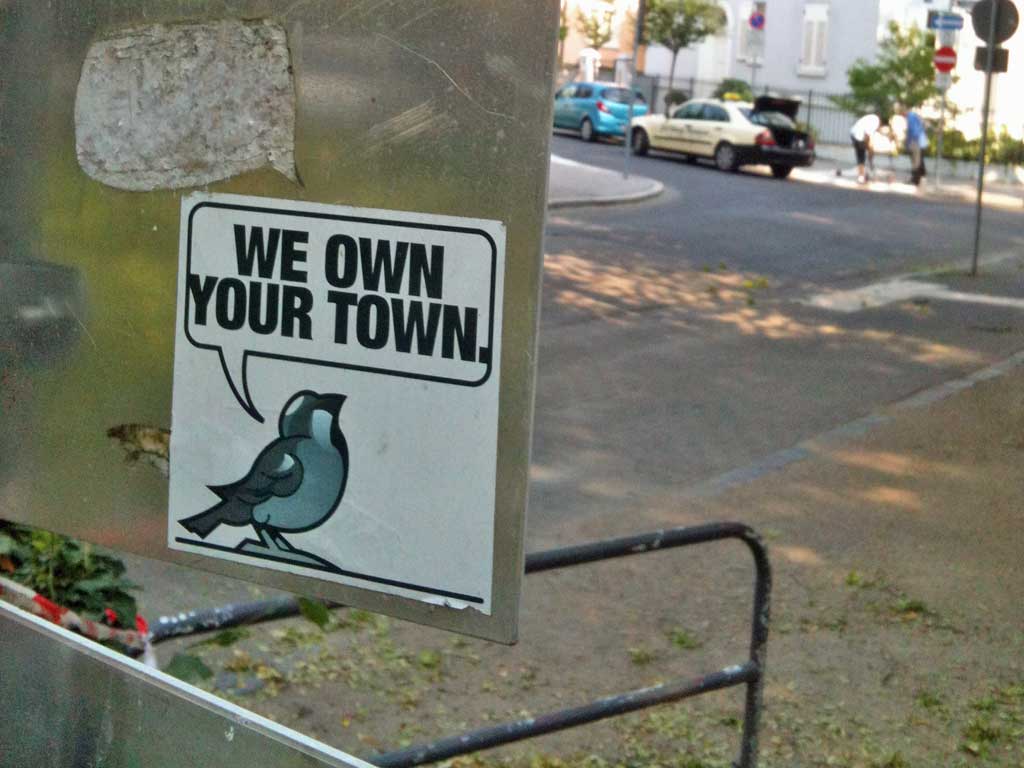 Aufkleber mit Vogel und „We own your town“-Sprechblase